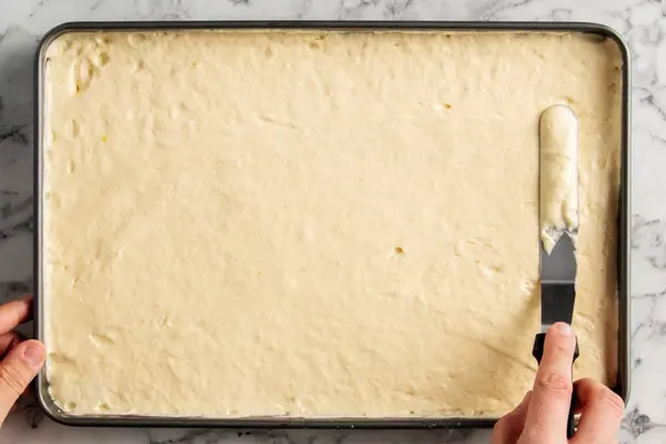 صاف کردن مایه کیک رولت انار در سینی فر با کاردک